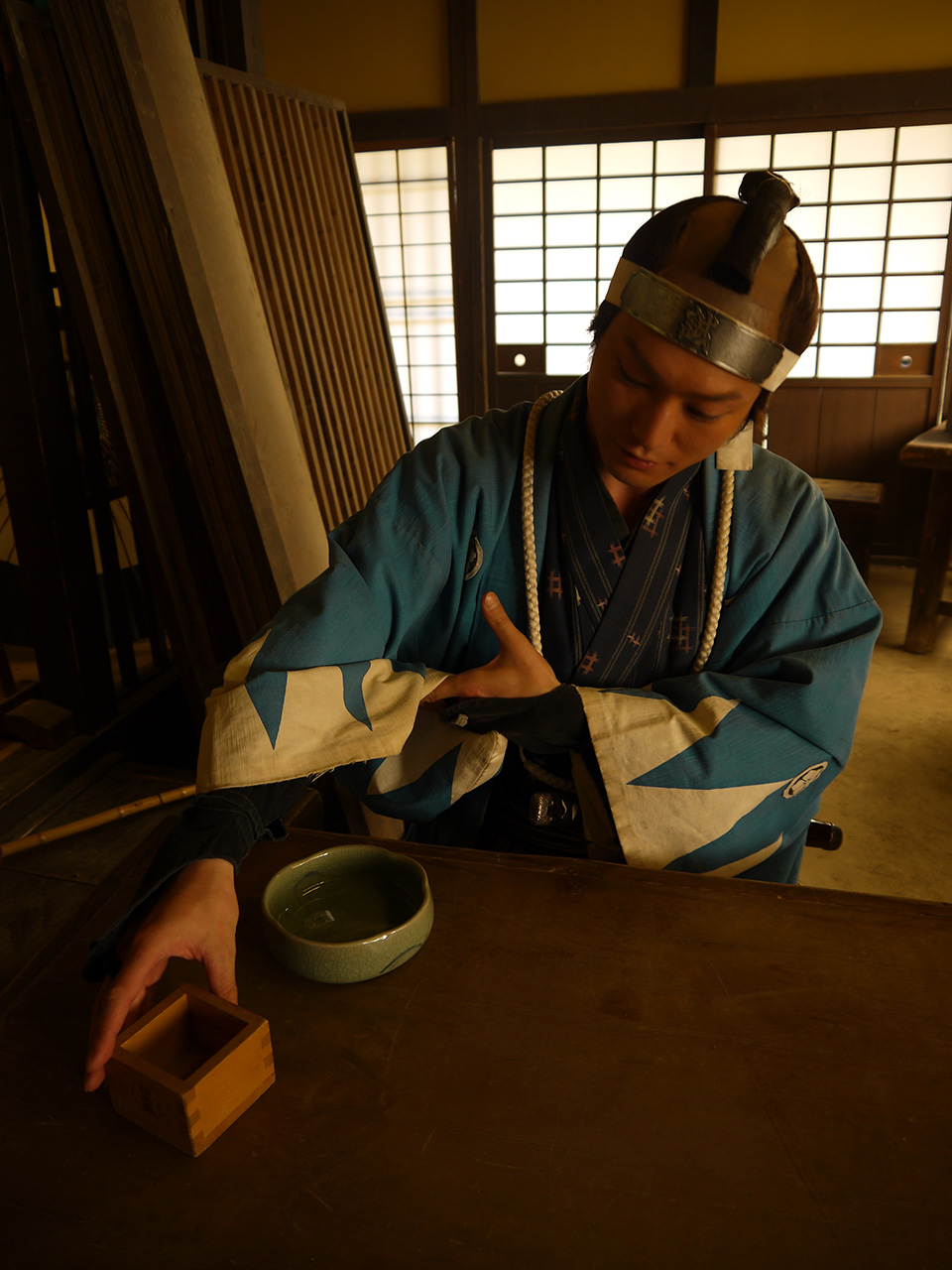 Takahiro Hotta in blue hakama reaching for cup tamoto