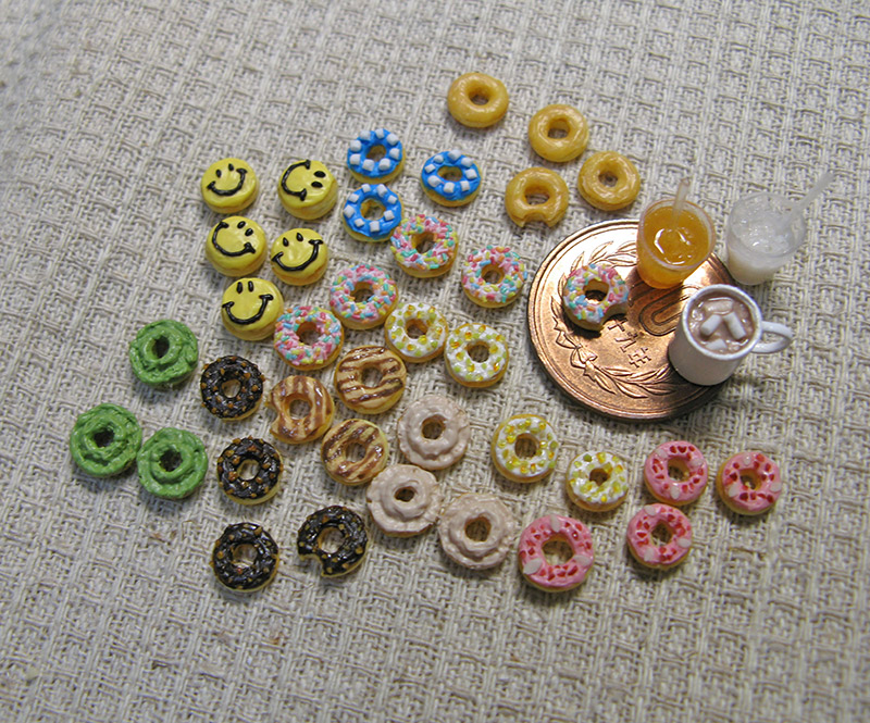 A group of miniature donuts and a 10 yen coin. About 6 mini donuts could fit on the coin.