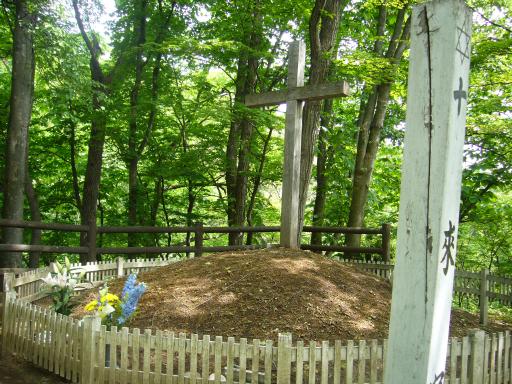 wooden cross on burial mound with white fence