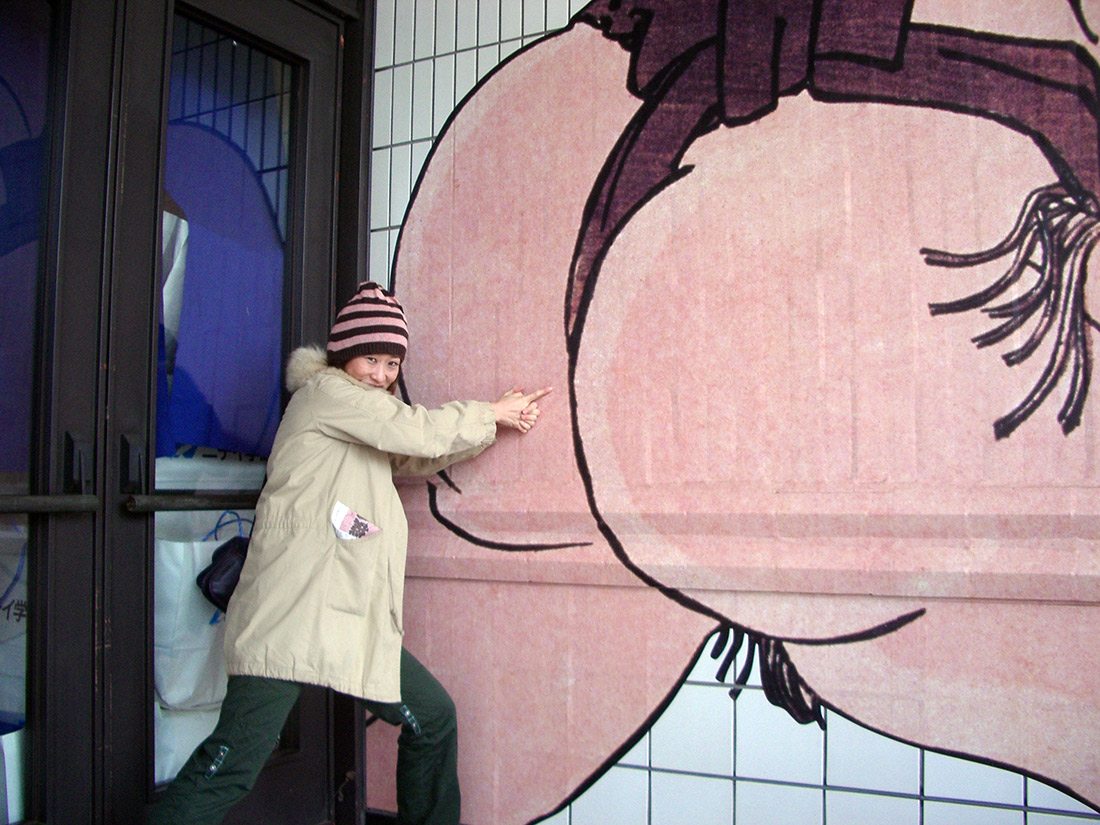 a woman giving kancho to a painting of a sumo wrestlers butt