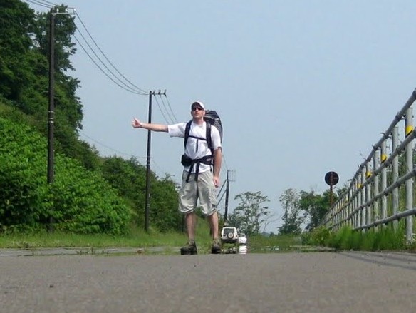 a man standing in the road hitchhiking in japan