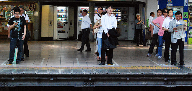 Japanese men standing in line at a train station