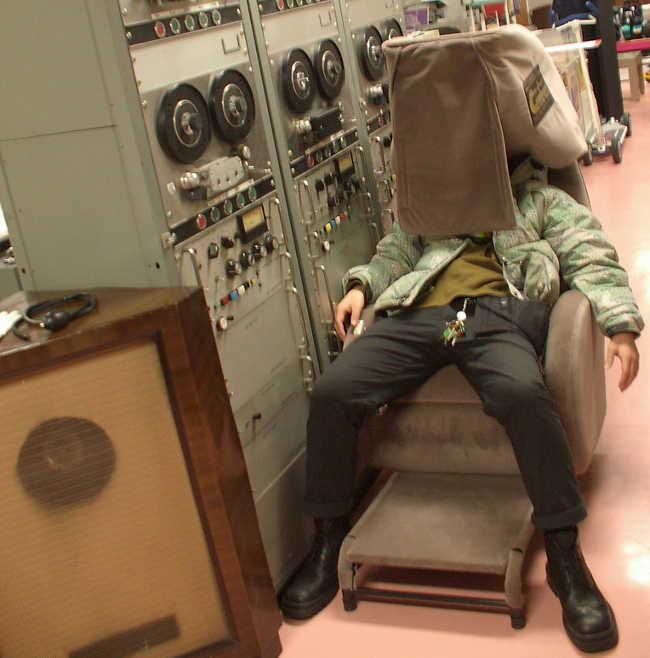 Man sitting in a large chair with cloth draped over his face