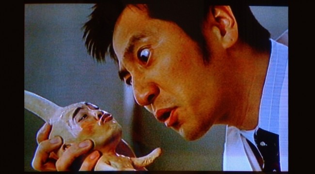 a japanese man staring at a baby creature