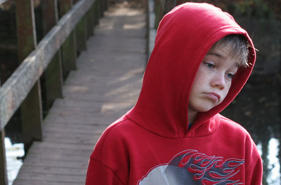 A despondent child in a red hoodie