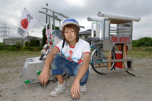 Japanese boy kneeling in front of his dekochari bicycle