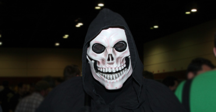 A man in a black hoodie wearing a skull mask