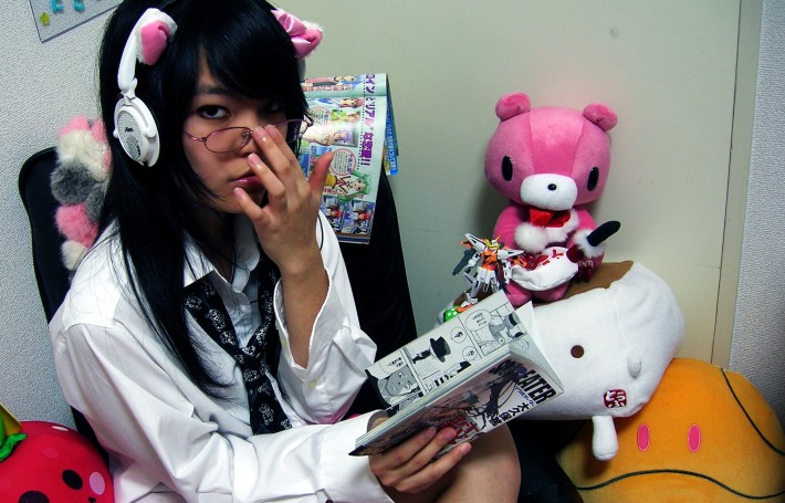 stereotypical otaku in japan reading manga surrounded by stuffed anime toys