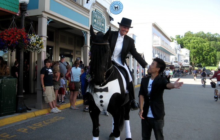 japanese man holding hand out next to man riding horse