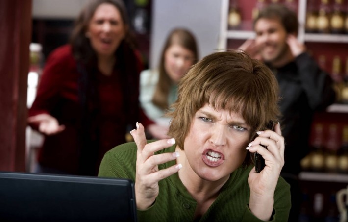 Stock image of a woman speaking angrily on the phone with irritated people behind her