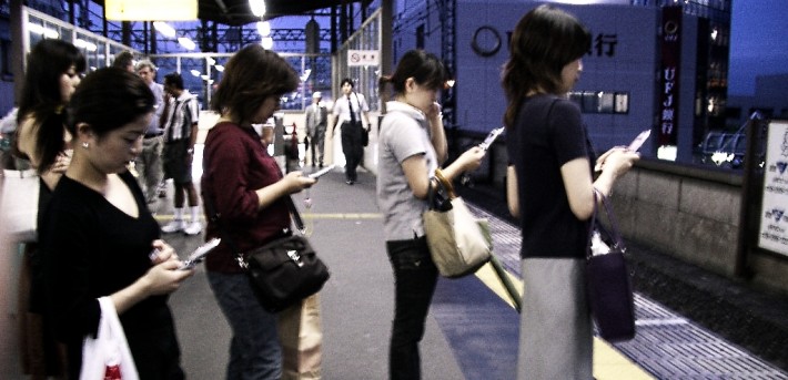 People on their phones while they’re waiting for a train to arrive