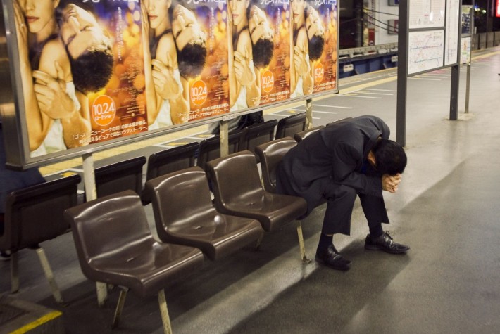 Man with his head in his hands on the benches at a train station