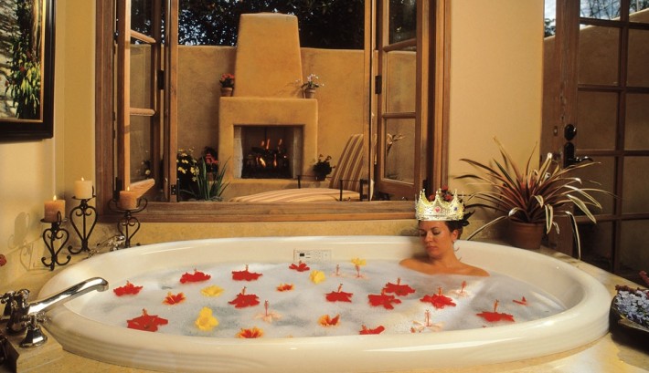 Woman with a crown in a bathtub filled with flowers