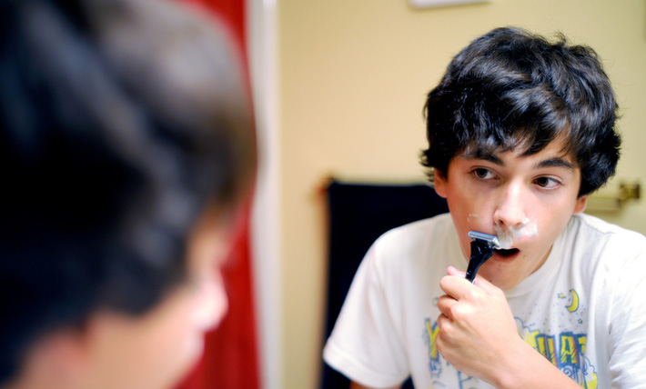 young boy with brown hair trying to shave