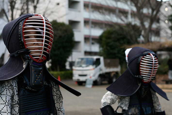 two people shoulders up kendo helmets and uniforms