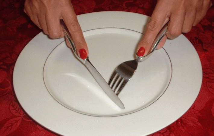 Woman using a knife and fork on an empty plate
