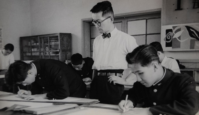 High school teacher sternly looks over his students studying