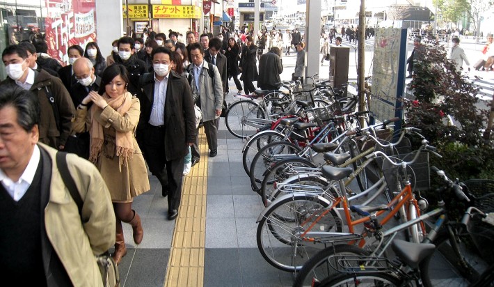 een groep Japanse voetgangers die chirurgische maskers dragen