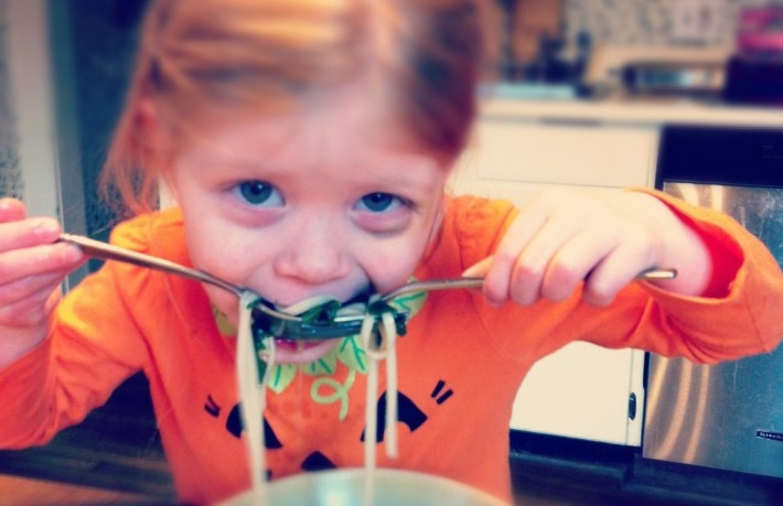 A toddler slurping her noodles