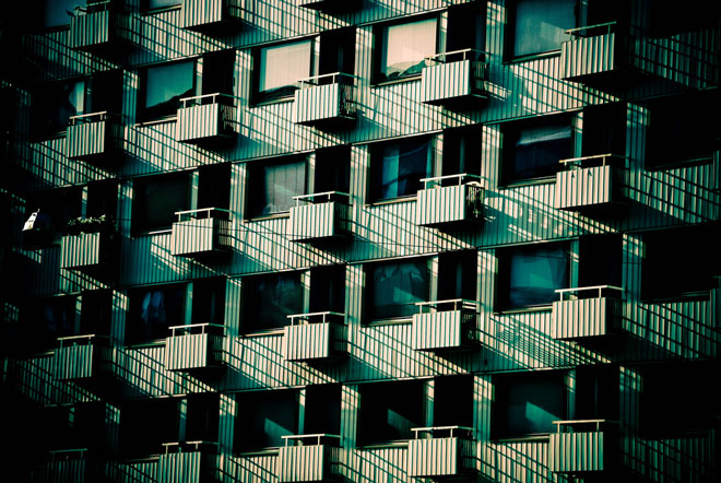 A heavily-filtered photograph of a Japanese apartment building from the outside where all the units look exactly the same