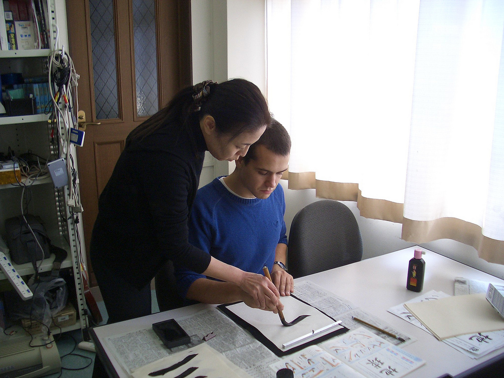 a professor helping a man with his japanese calligraphy