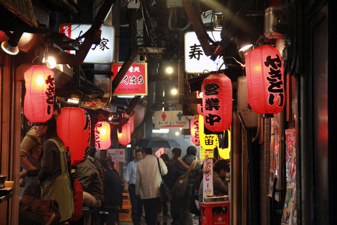 japanese piss alley in tokyo with red lanterns and wandering people