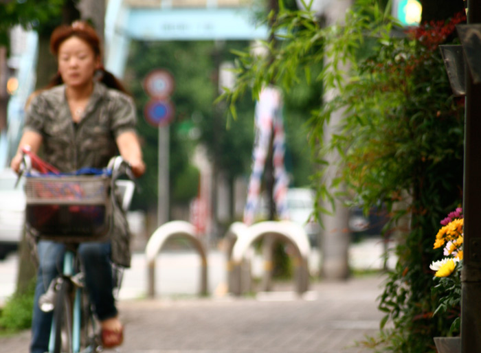 japanese woman riding a bicycle down the street