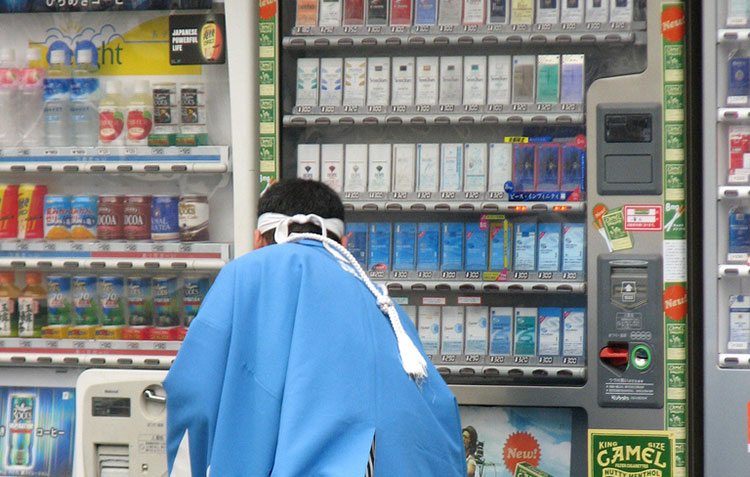 Man in Japan purchasing cigarettes at a vending machine