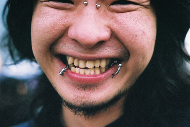 A smiling Japanese man with multiple piercings