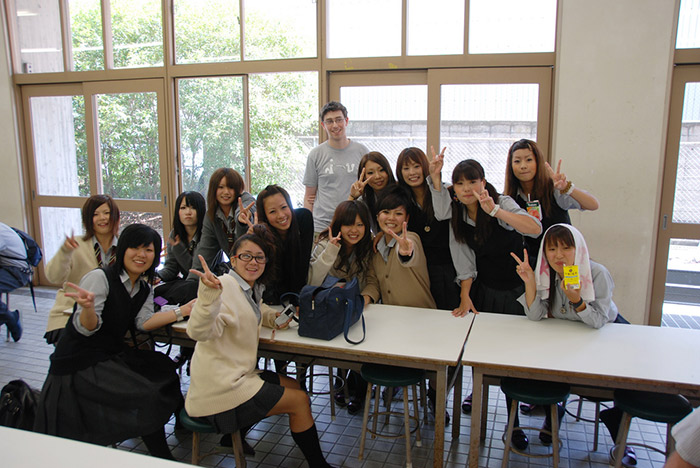 thirteen students from japan at tables posing for the camera