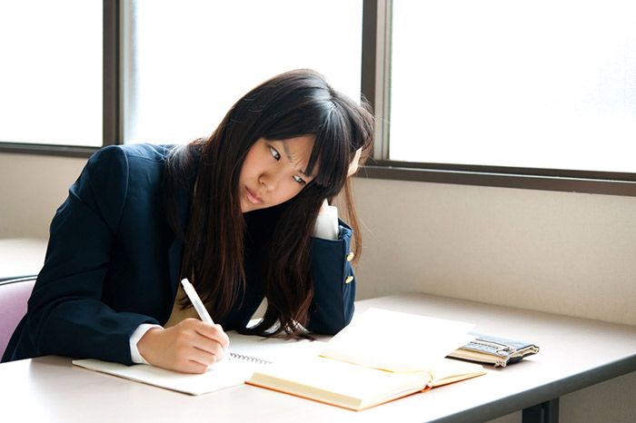 japanese school girl sitting at desk with head propped up