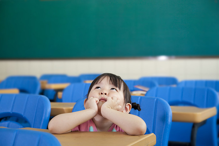 japanese schoolgirl sitting in japanese classroom looking up at ceiling