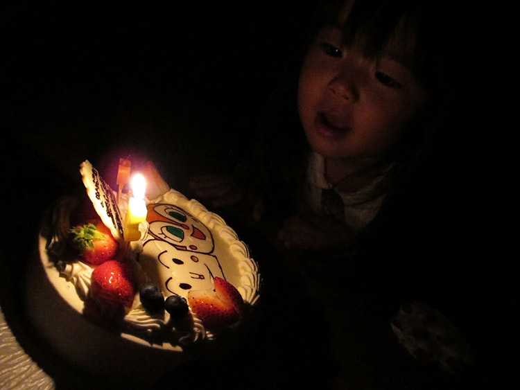 A young Japanese girl prepares to blow out birthday candles