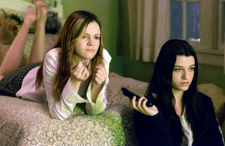 two girls watching tv looking bored pass the remote