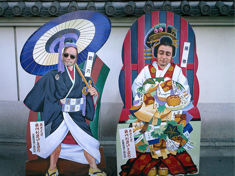 foreigners stand behind large cutouts of traditional Japanese outfits