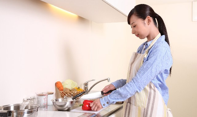 woman in apron chopping a red pepper