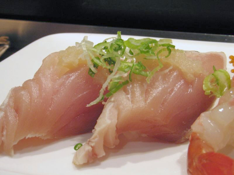 raw white tuna slices on plate with sliced green onion