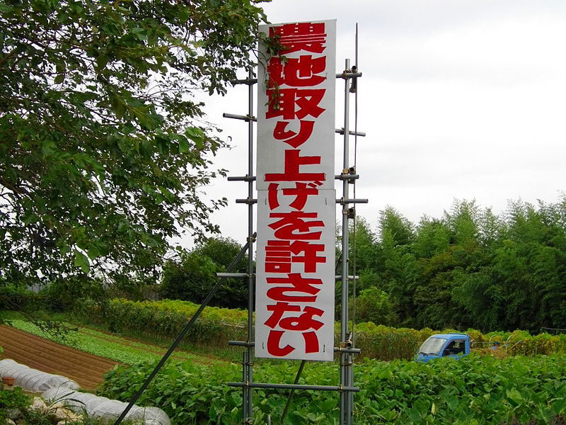 White sign with red writing posted in a field