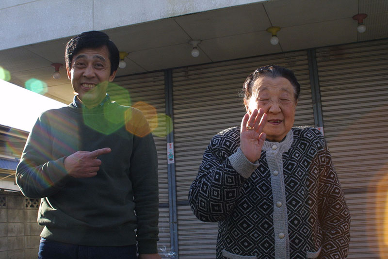 An elderly Japanese couple waving goodbye