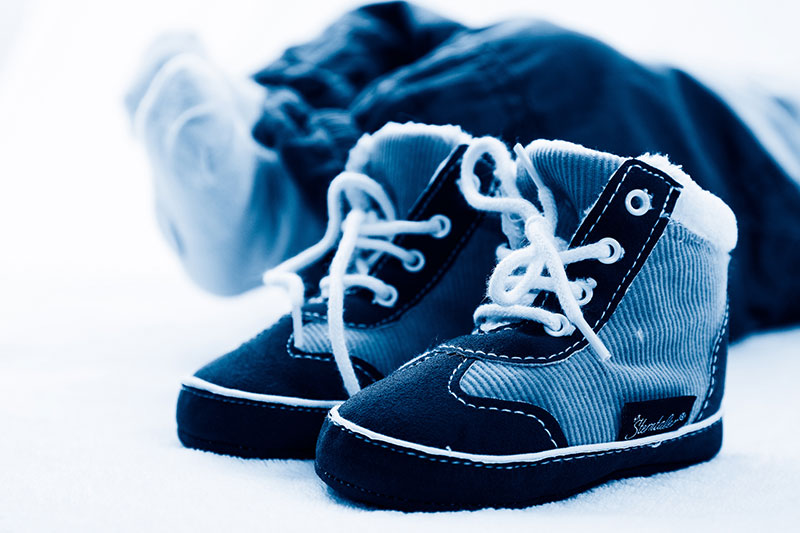 Baby shoes with a fallen-over baby in the background