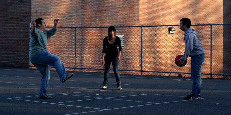 three people playing four square on a blacktop