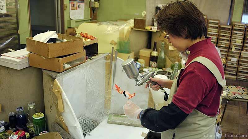employee airbrushing wax tempura
