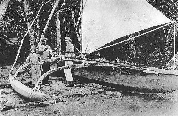 Grainy black and white photo of three men standing by an outrigger canoe