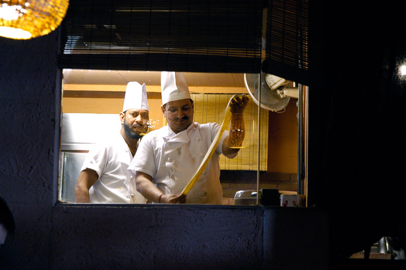 two chefs seen through window of Indian restaurant