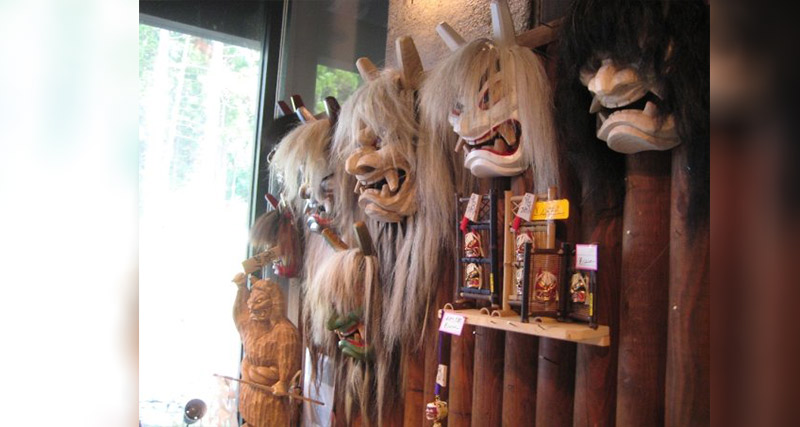 White demon and ogre masks hanging on a wall