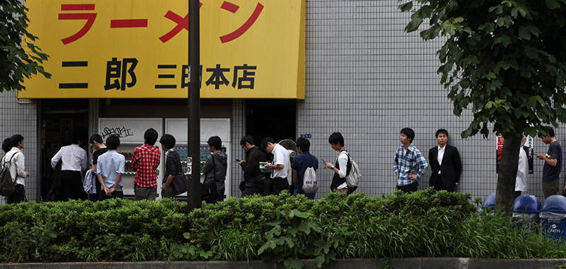 men lining up outside ramen store