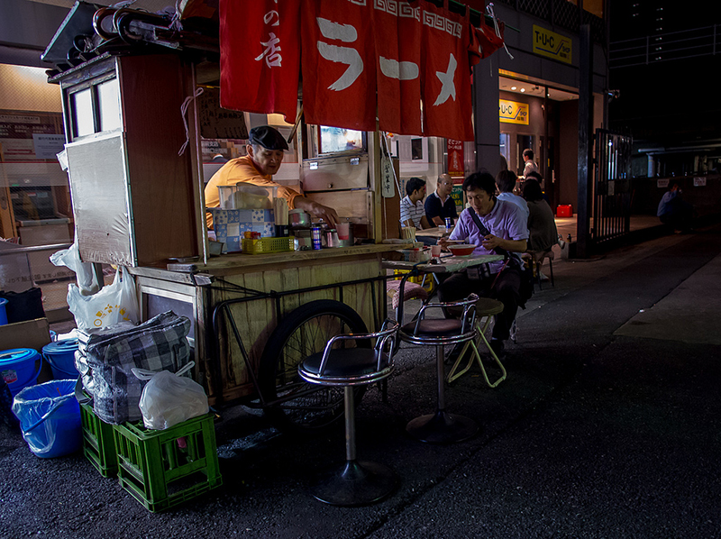 man eating ramen at street stand