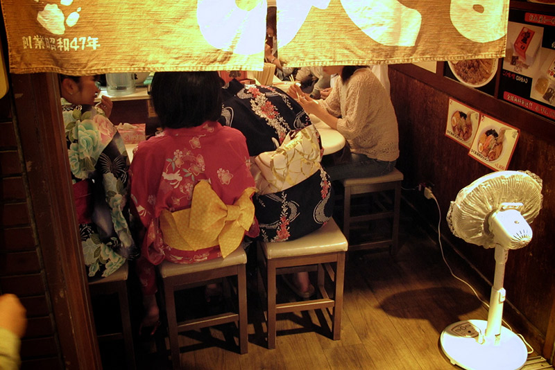 young girls wearing kimonos eating at japanese shop