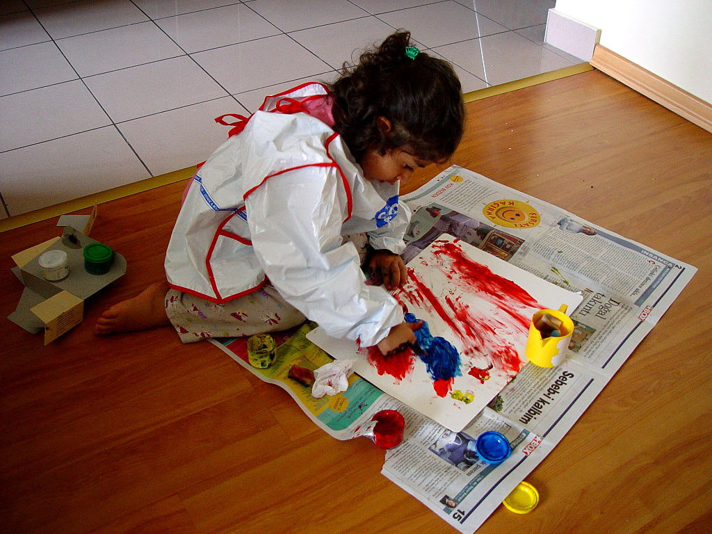 A child finger painting on the floor