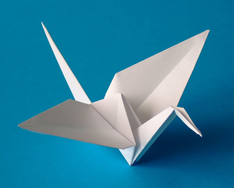 An small origami crane on a blue background